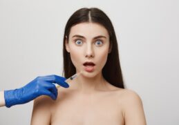 shocked woman open mouth stare worried while take bottox injection lip