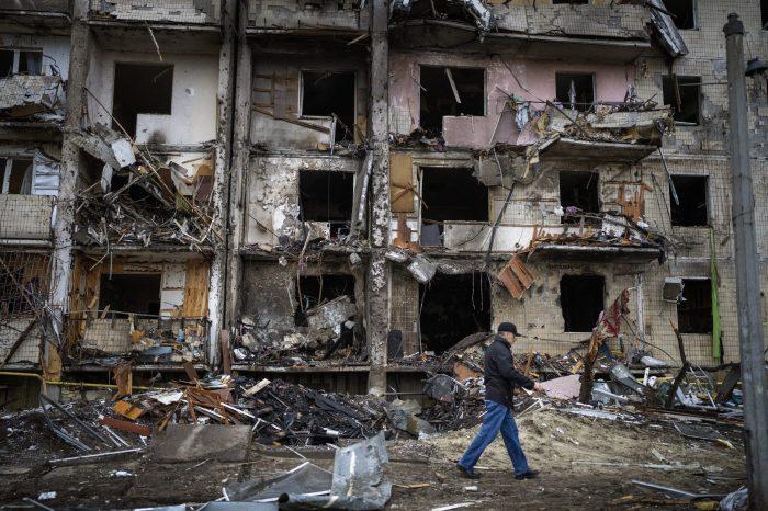 A man walks past a building damaged by the impact of a projectile in Kiev Ukraine