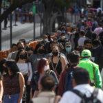 People walk with face masks on one of the avenues of the Historic Center in Mexico City