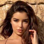 Demi Rose lies face down and tans topless on the sand
