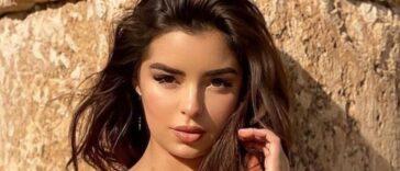 Demi Rose lies face down and tans topless on the sand