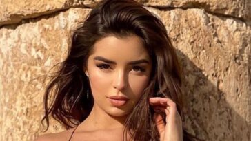 Demi Rose lies face down and tans topless on the sand