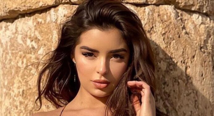 Demi Rose lies face down and tans topless on the sand