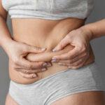 close up hands holding belly fat