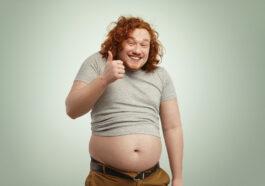 fat overweight redhead caucasian man undersized t shirt showing thumps up smiling