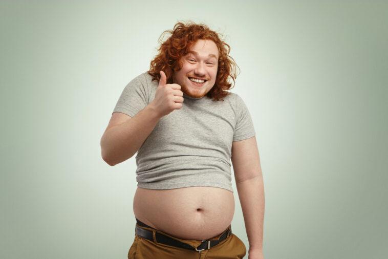 fat overweight redhead caucasian man undersized t shirt showing thumps up smiling