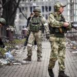 Russian soldiers walk down the street of Mariupol