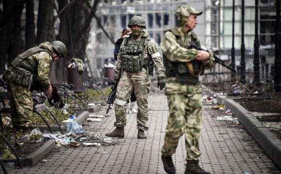 Russian soldiers walk down the street of Mariupol