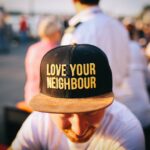 Coping with a Divorced Crybaby Neighbor: A Guide to Handling the Situation man wearing black cap with love your neighbour print during daytime