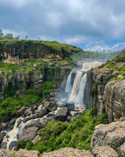 a waterfall in the middle of a lush green valley