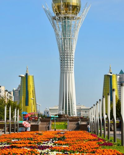 a very tall tower with a golden dome in the middle of a field of flowers
